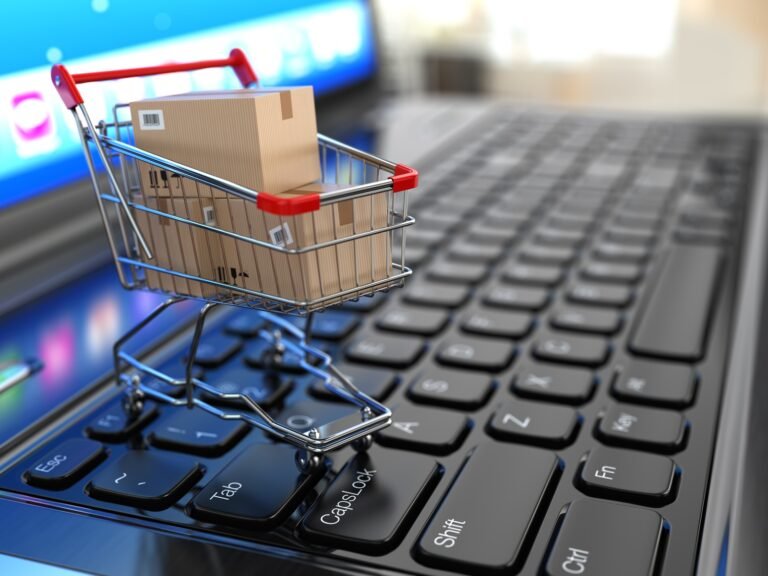E-commerce. Shopping cart with cardboard boxes on laptop